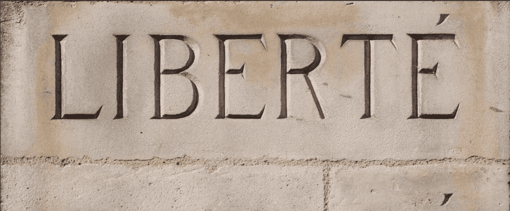 Sculpture représentant le mot "Liberté" en relief sur un mur en pierre.